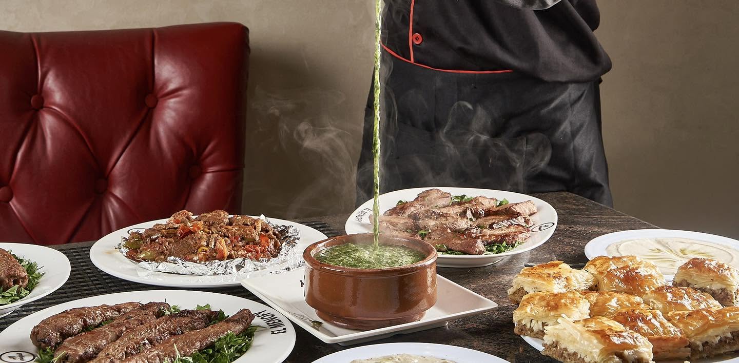 El Menofy food spread with molokhia being poured, grilled meats and golden pastry